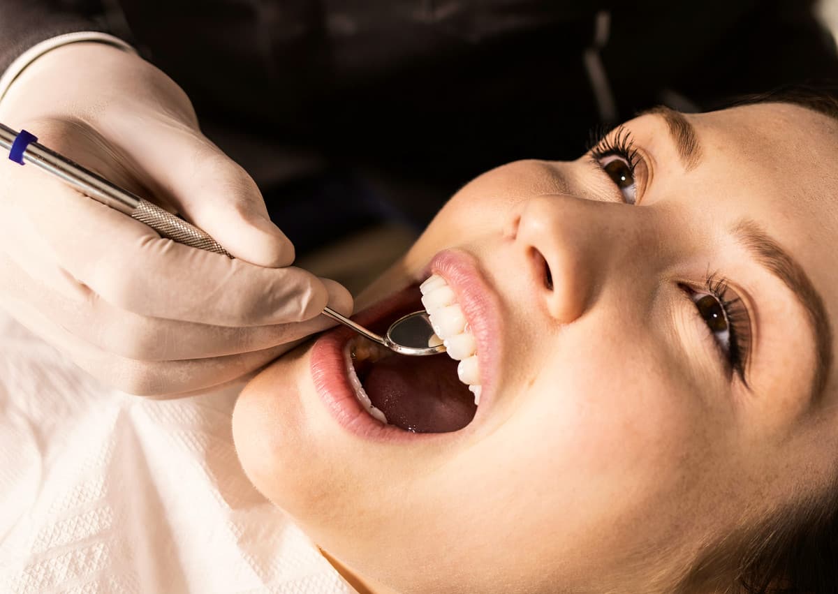 Patient receiving oral surgery with dental professional examining teeth.