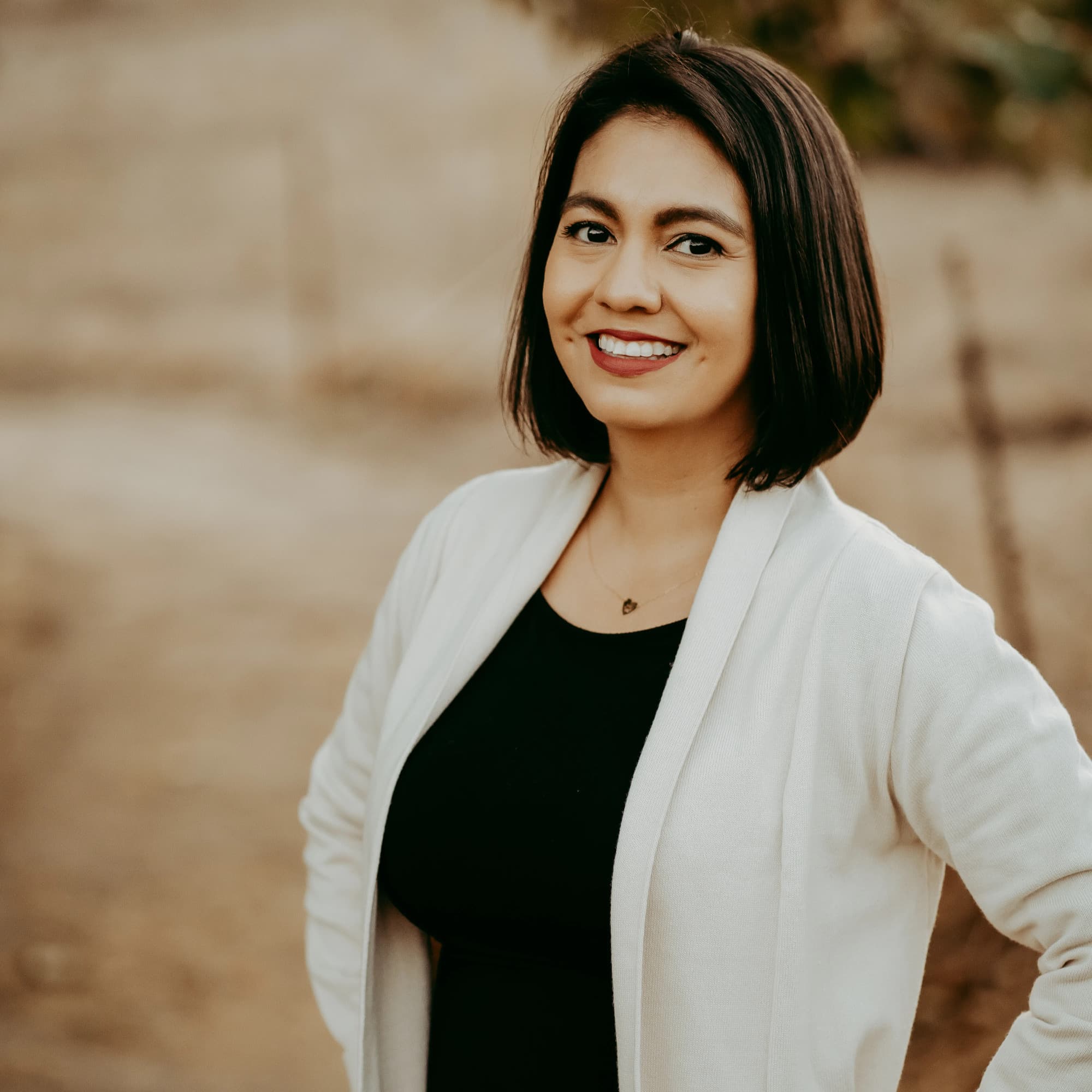 Gisselle Chingirian, Registered Dental Hygienist, smiling outdoors in a black top and white cardigan, embodying a compassionate approach to dental care.