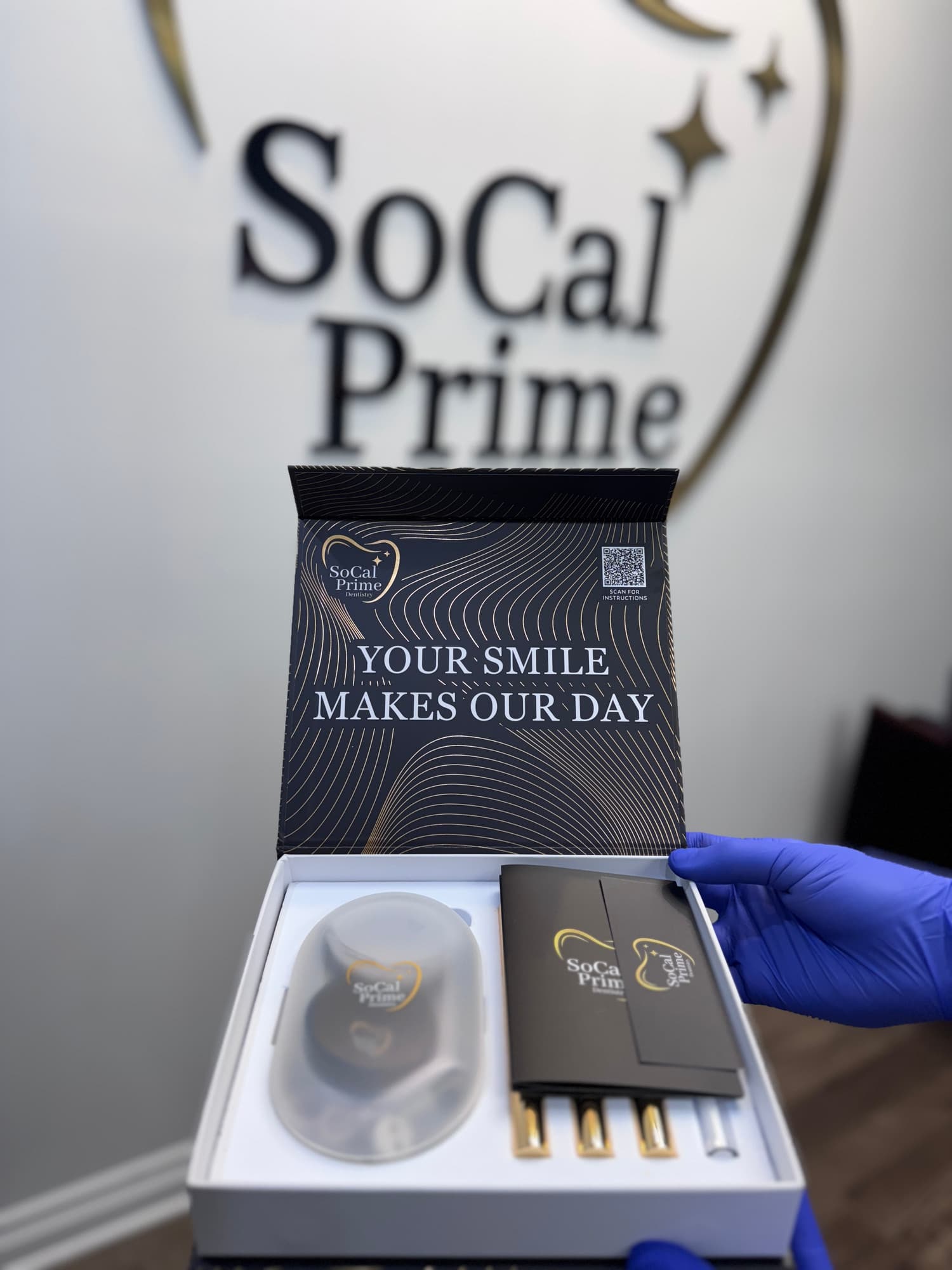SoCal Prime Dentistry take-home teeth whitening kit with branding, featuring a message "YOUR SMILE MAKES OUR DAY," and tools for dental care, emphasizing the promotional offer for new patients.